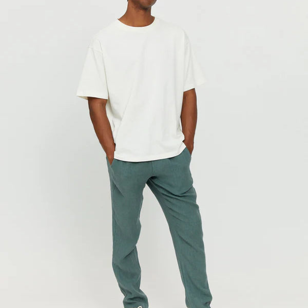 Junger Mann in weißem Shirt und blauen Hosen.