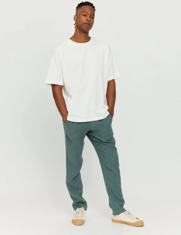 Junger Mann in weißem Shirt und blauen Hosen.