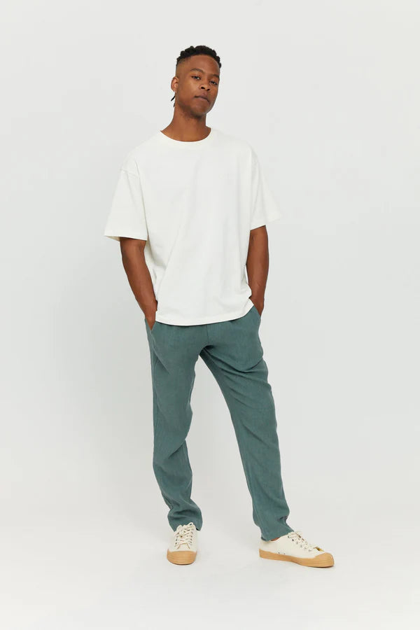 Junger Mann in weißem Shirt und blauen Hosen.