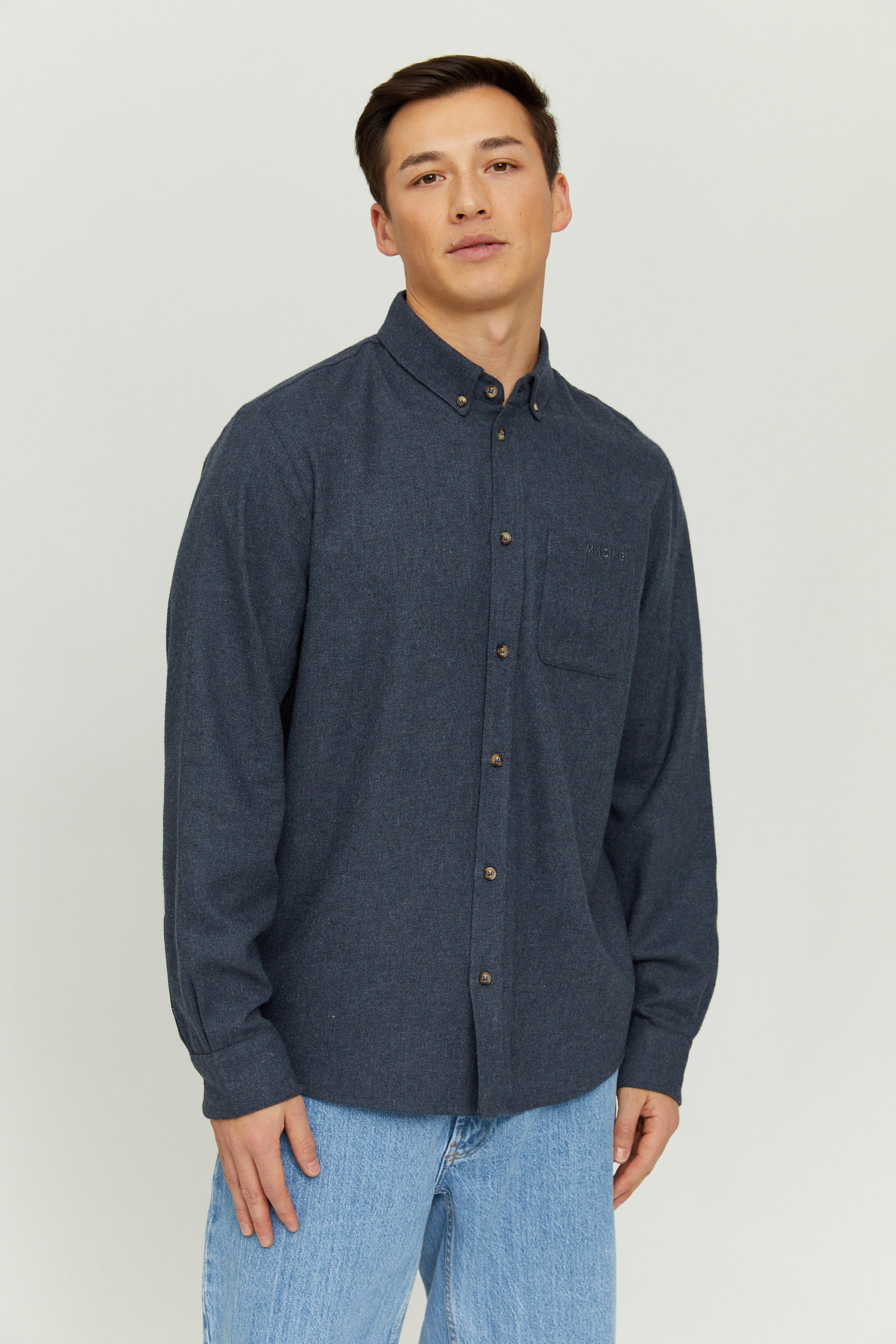 Mann in blauem Hemd und Jeans steht