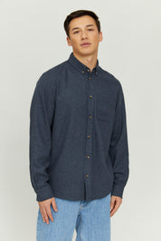 Mann in blauem Hemd und Jeans steht