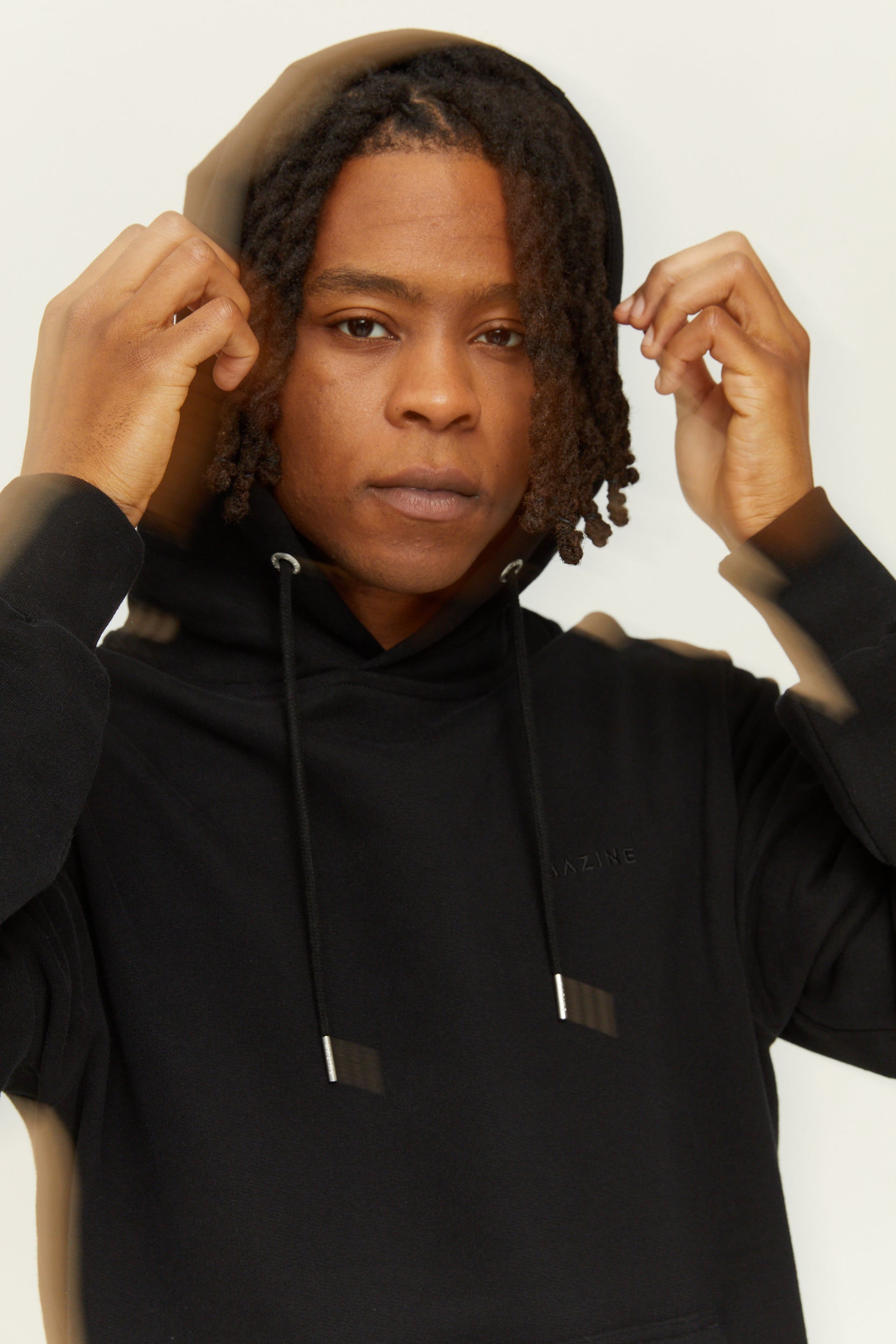 Person justiert Kapuze ihres schwarzen Hoodies