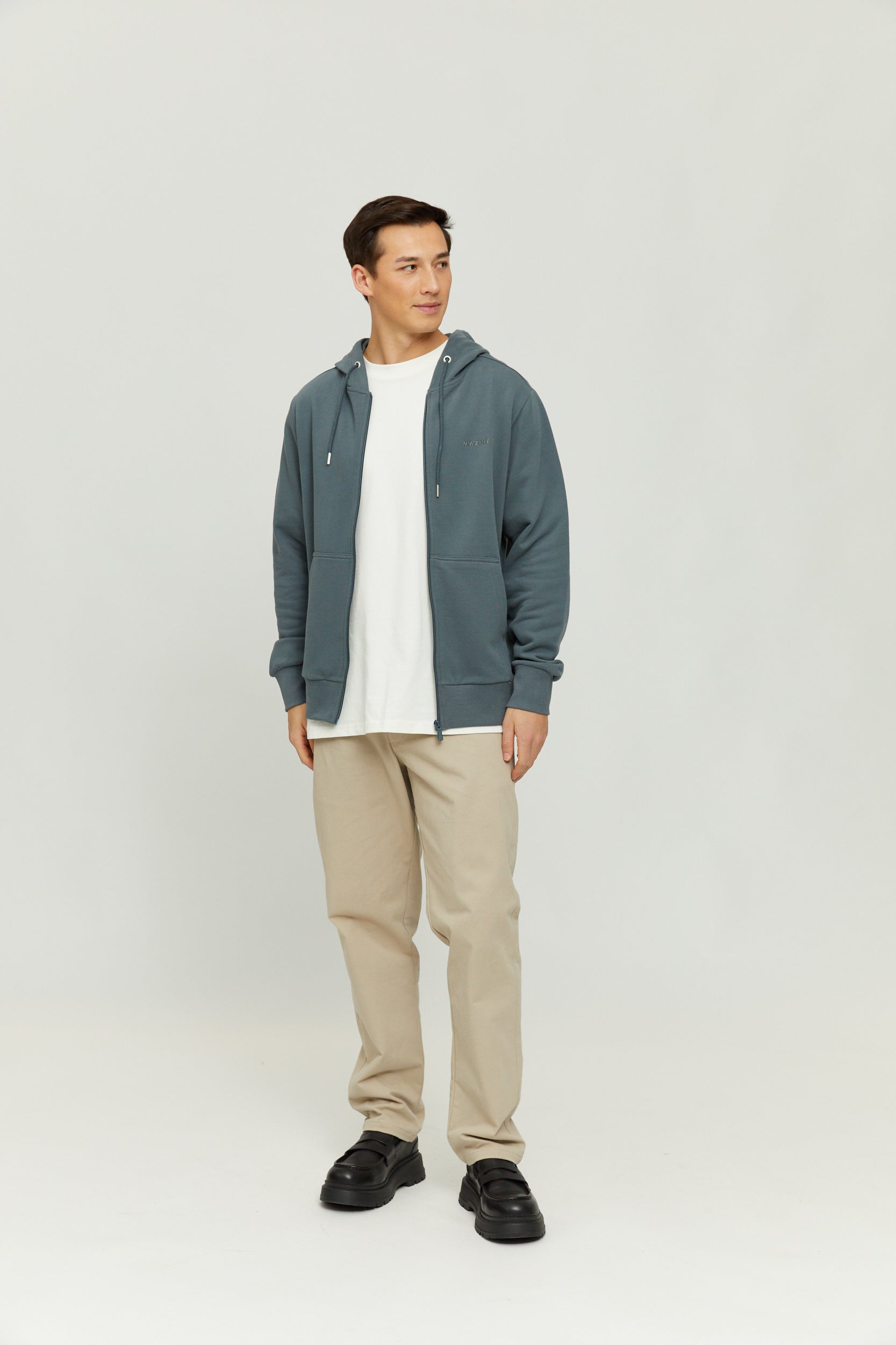 Mann in blauer Jacke und beigen Hosen steht