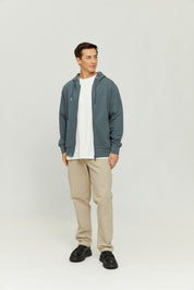 Mann in blauer Jacke und beigen Hosen steht