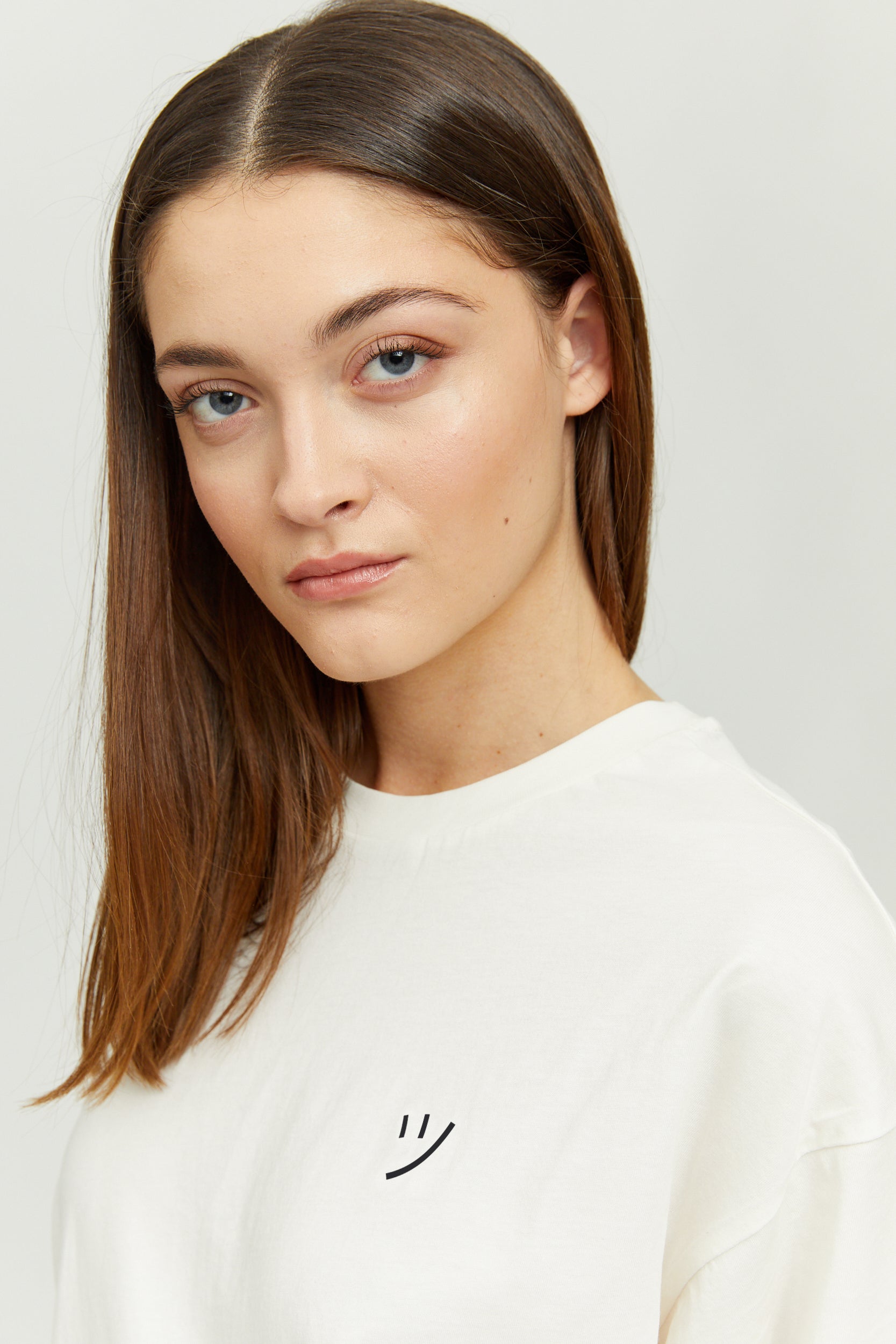 Junge Frau in weißem T-Shirt mit subtilem Smiley