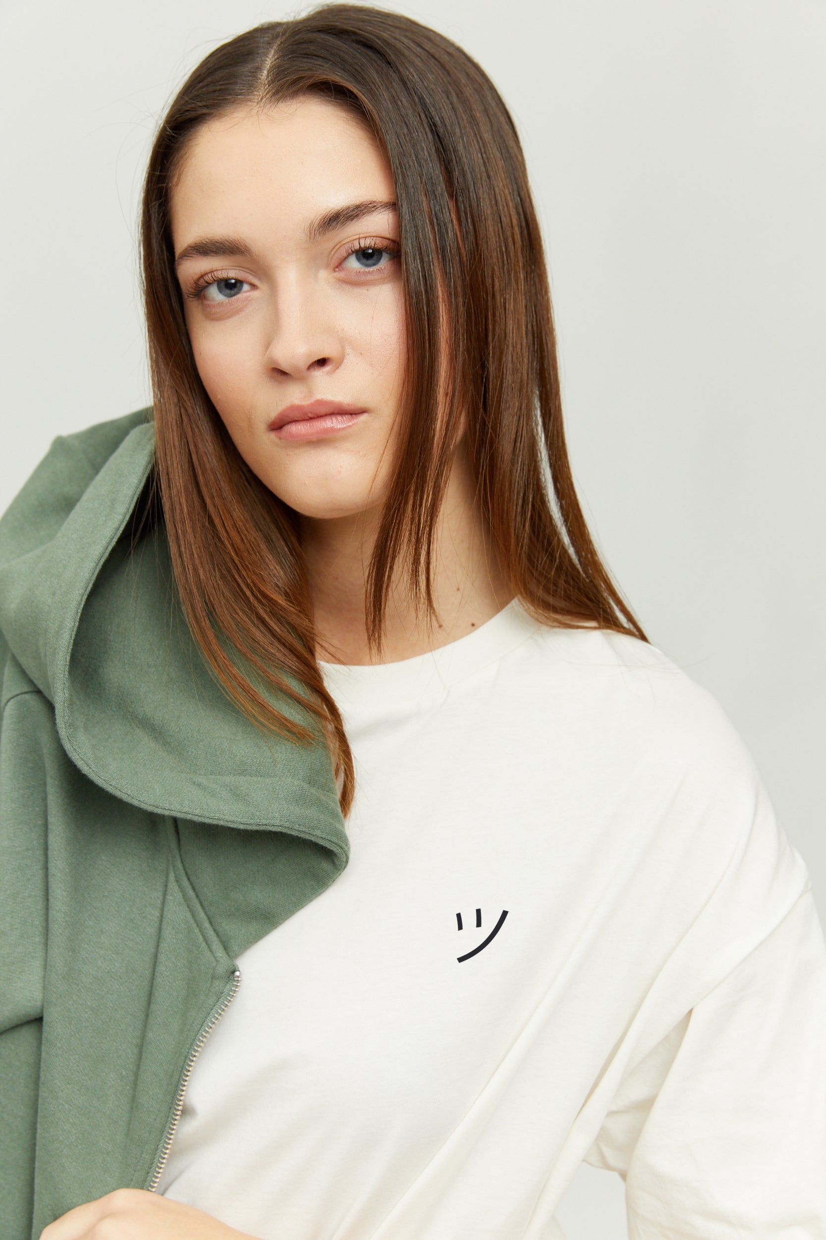 Junge Frau trägt weißes Shirt und grüne Jacke