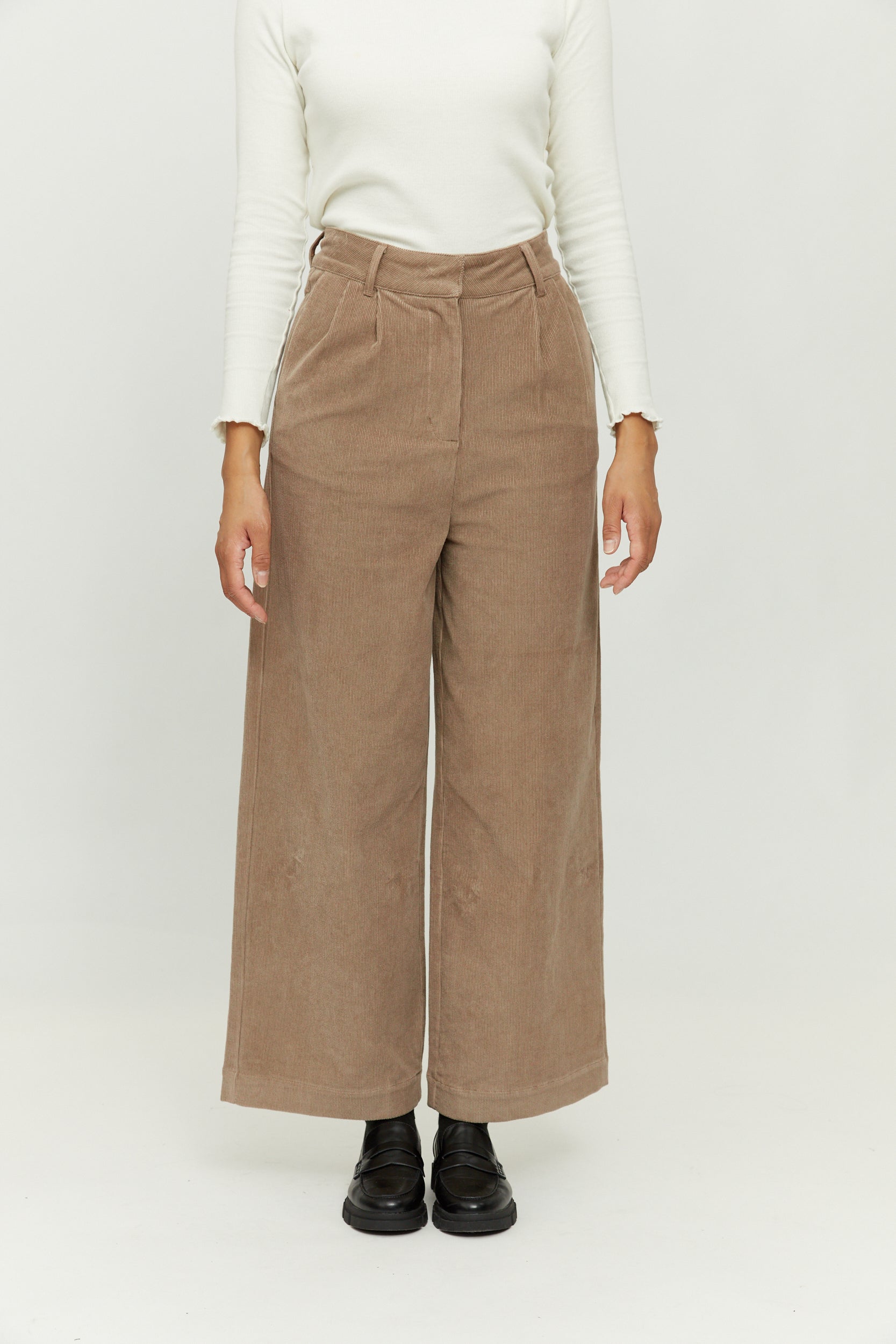 Frau trägt braune Hose und weißen Pullover