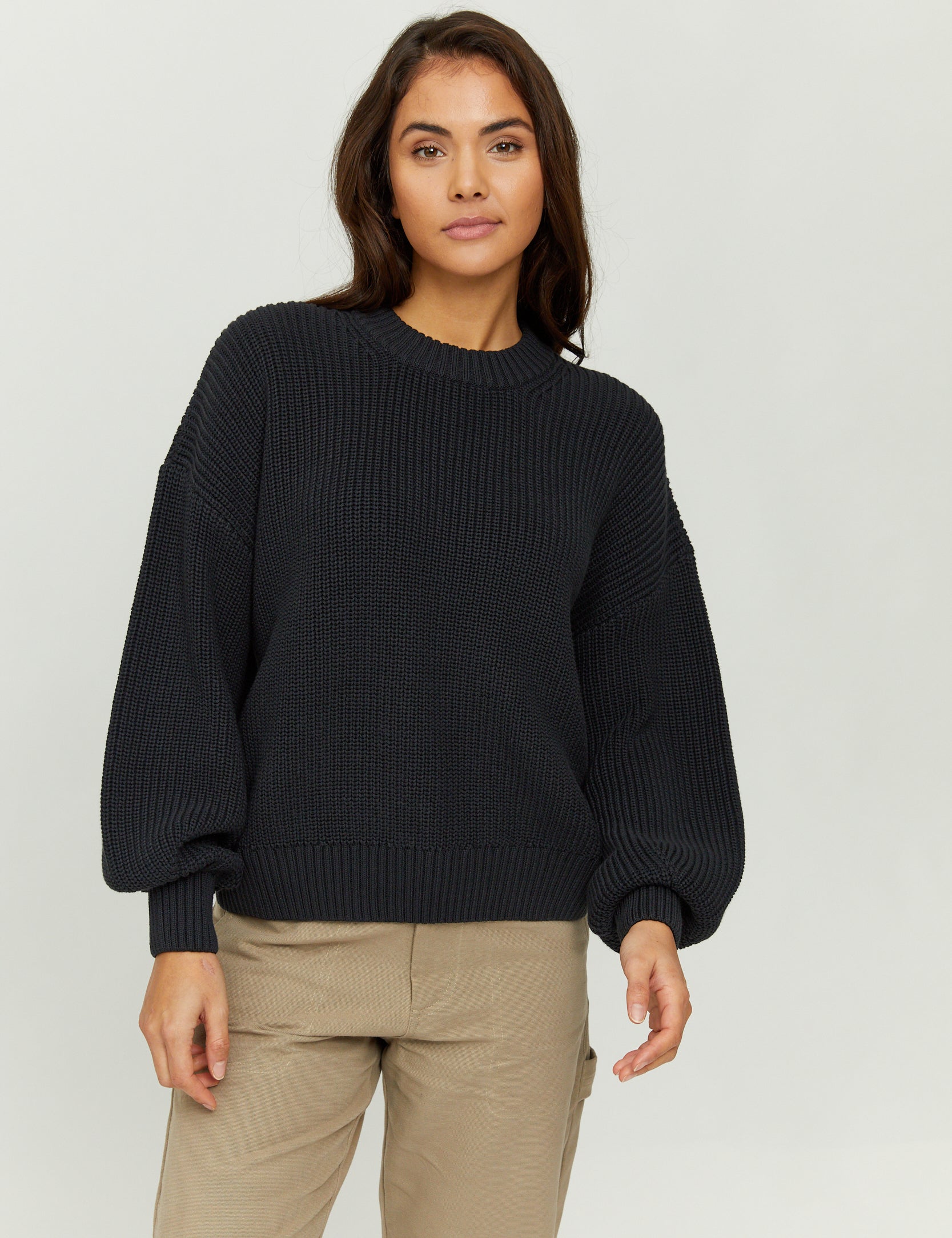 Frau in schwarzem Pullover und beigen Hosen