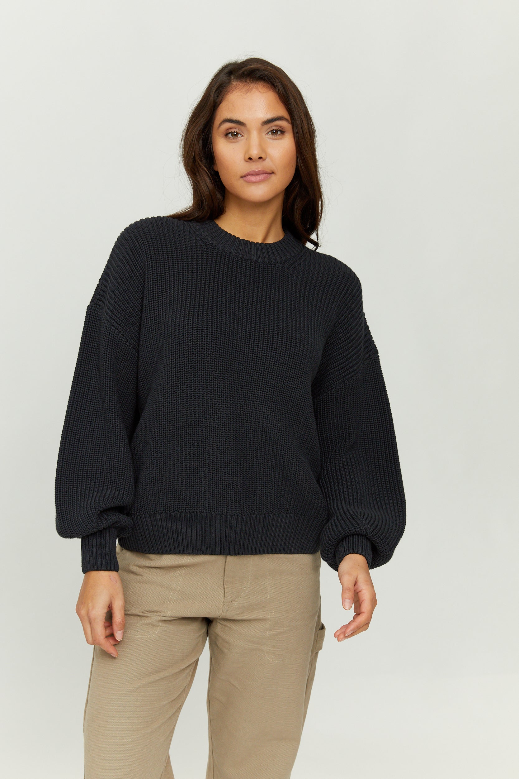Frau in schwarzem Pullover und beigen Hosen