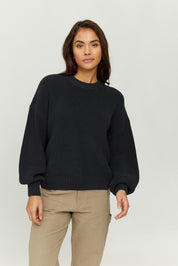 Frau in schwarzem Pullover und beigen Hosen