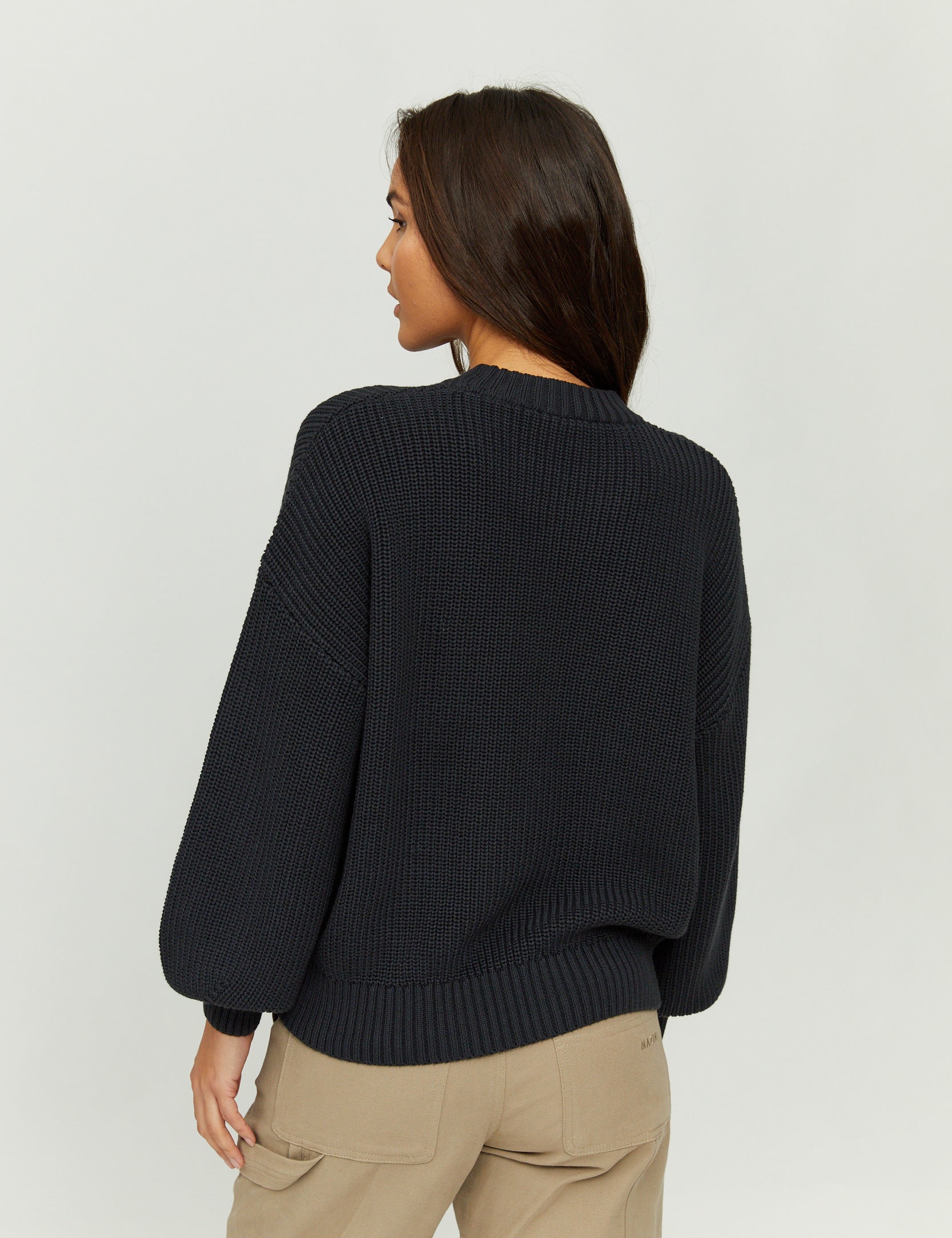 Frau trägt schwarzen Pullover, von hinten