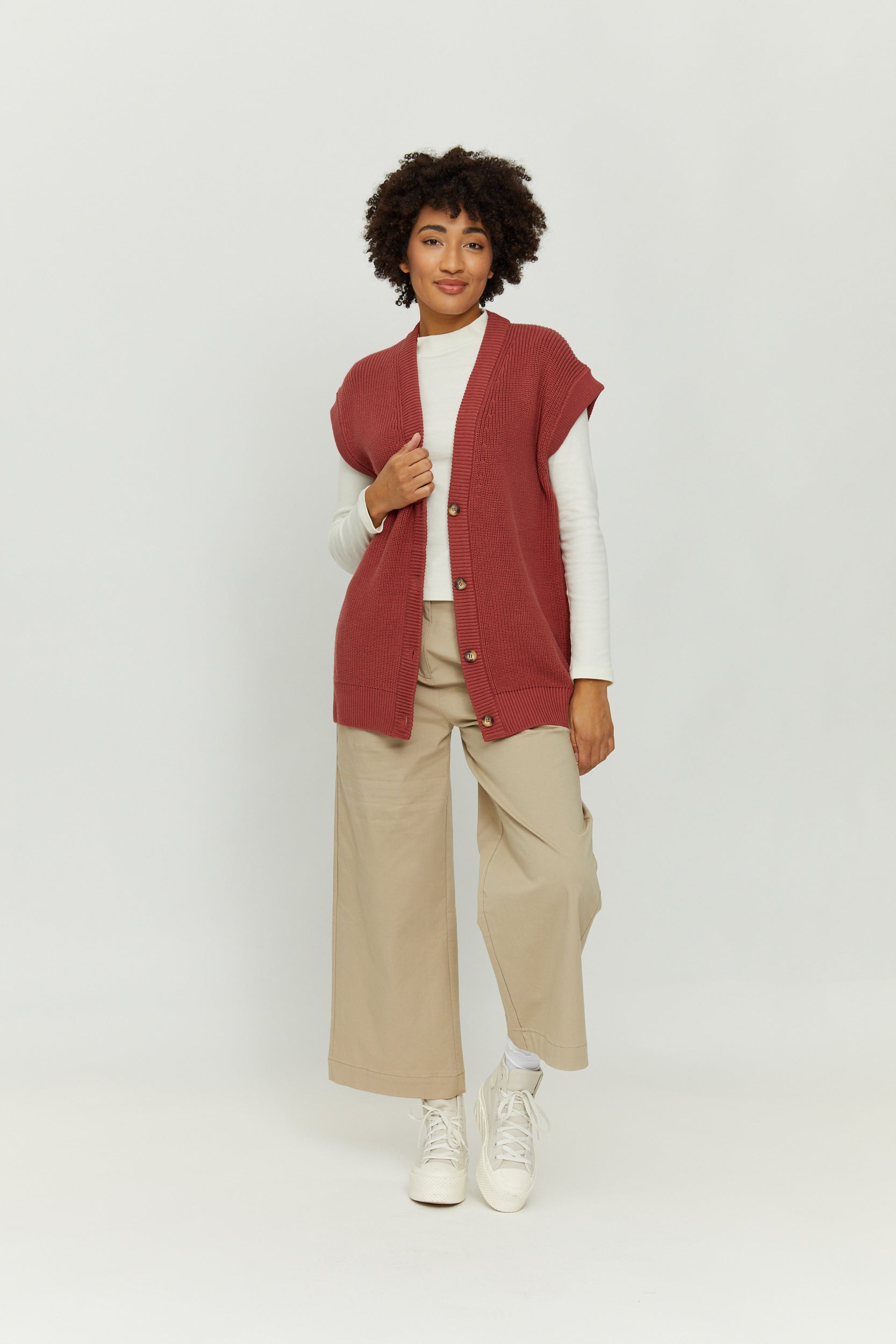 Frau in beiger Hose und rotem Strickweste