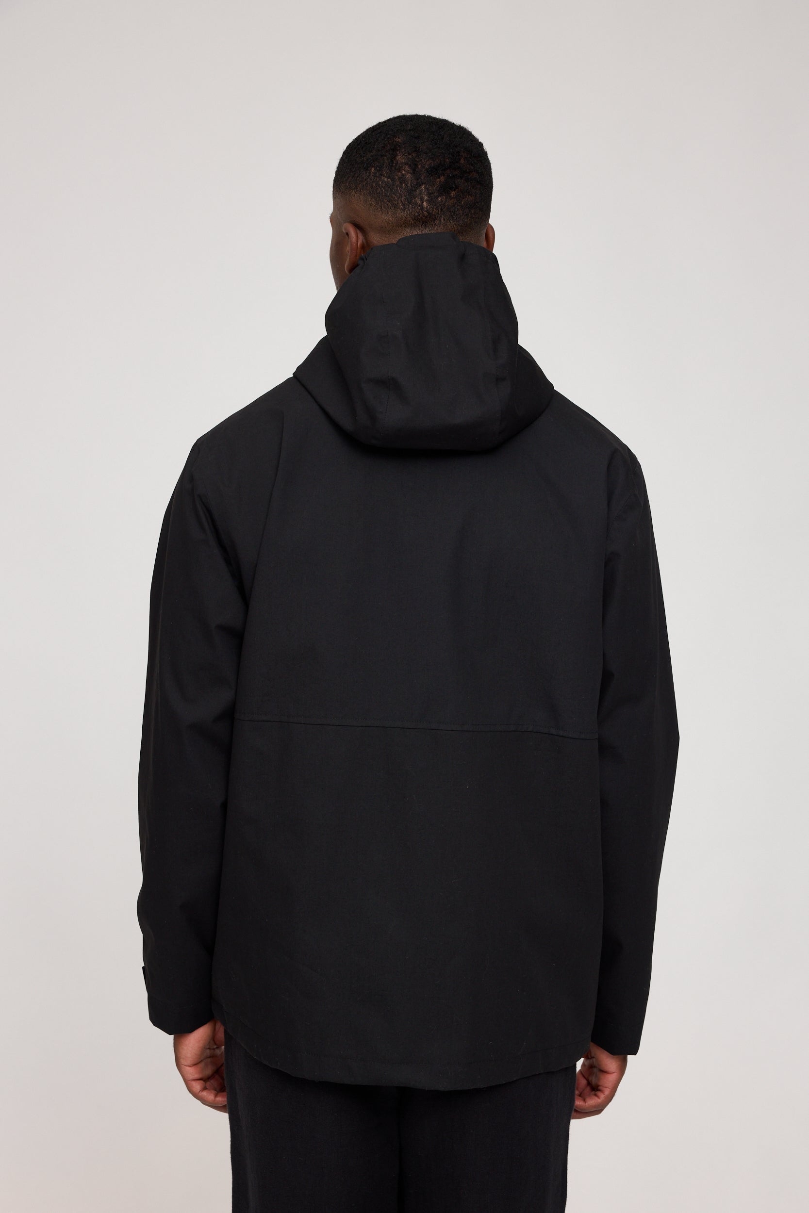 Mann trägt schwarze Kapuzenjacke, Rückansicht