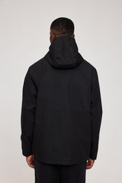 Mann trägt schwarze Kapuzenjacke, Rückansicht