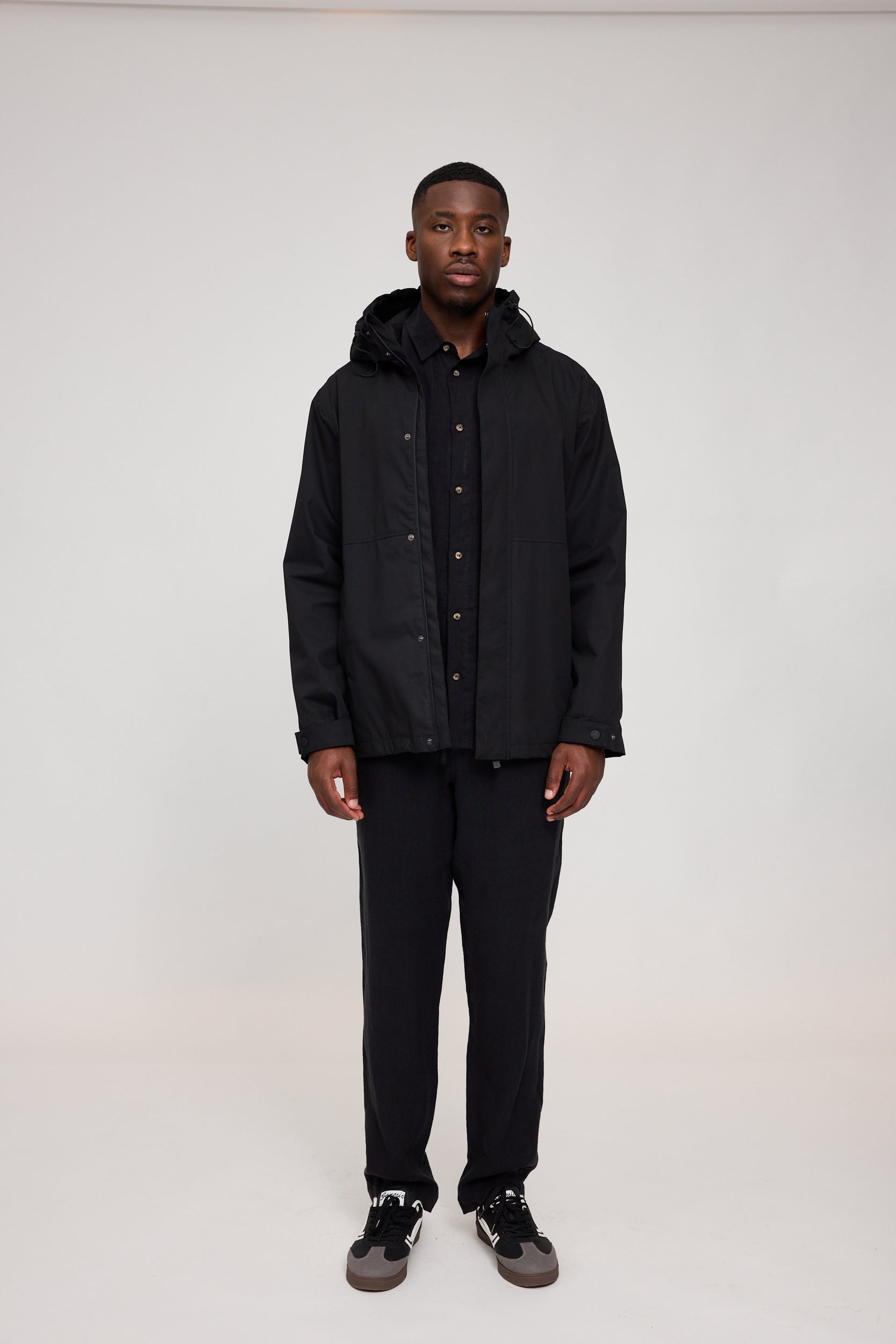 Mann in schwarzer Jacke und Hose steht