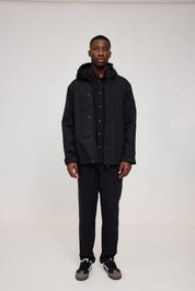 Mann in schwarzer Jacke und Hose steht