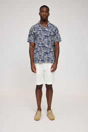 Mann in gemustertem Hemd und weißen Shorts