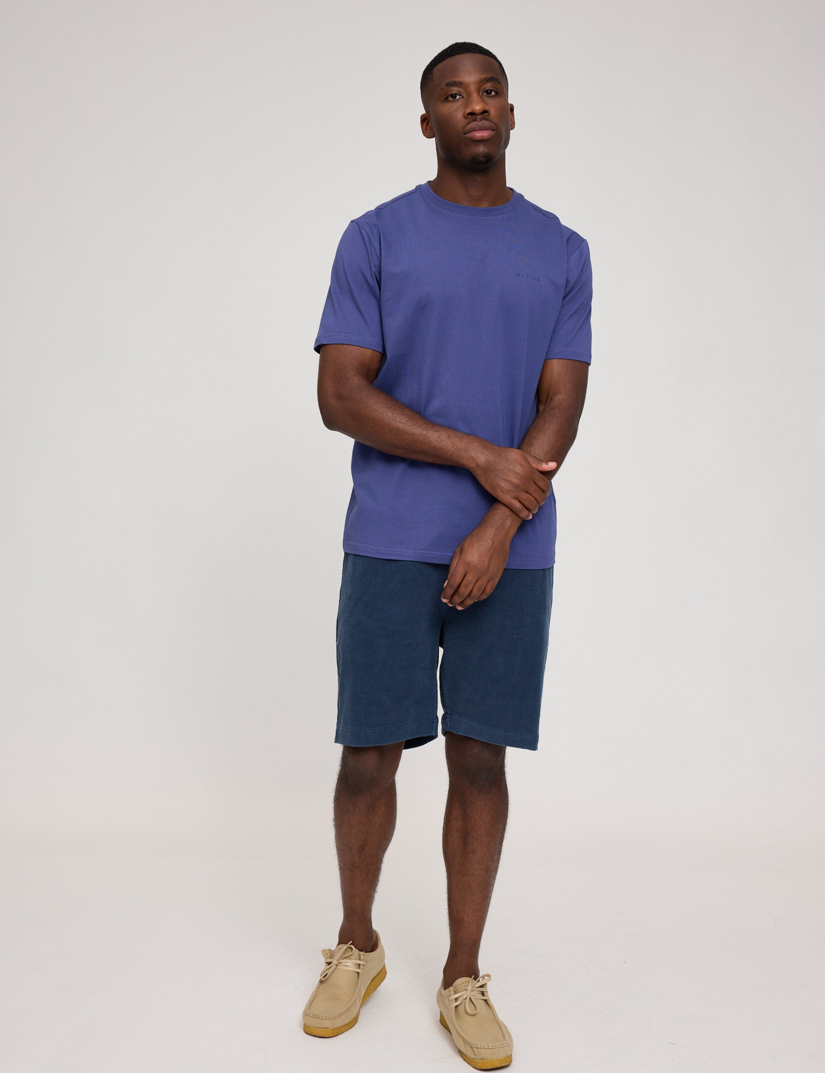 Mann in blauem Shirt und Shorts steht gerade