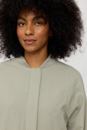 Frau mit lockigem Haar und grüner Jacke