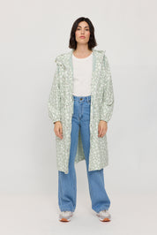 Frau in Jeans und gemustertem Mantel steht