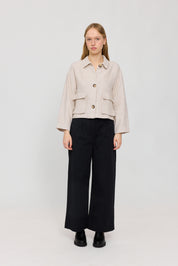Frau in beiger Jacke und schwarzen Hosen
