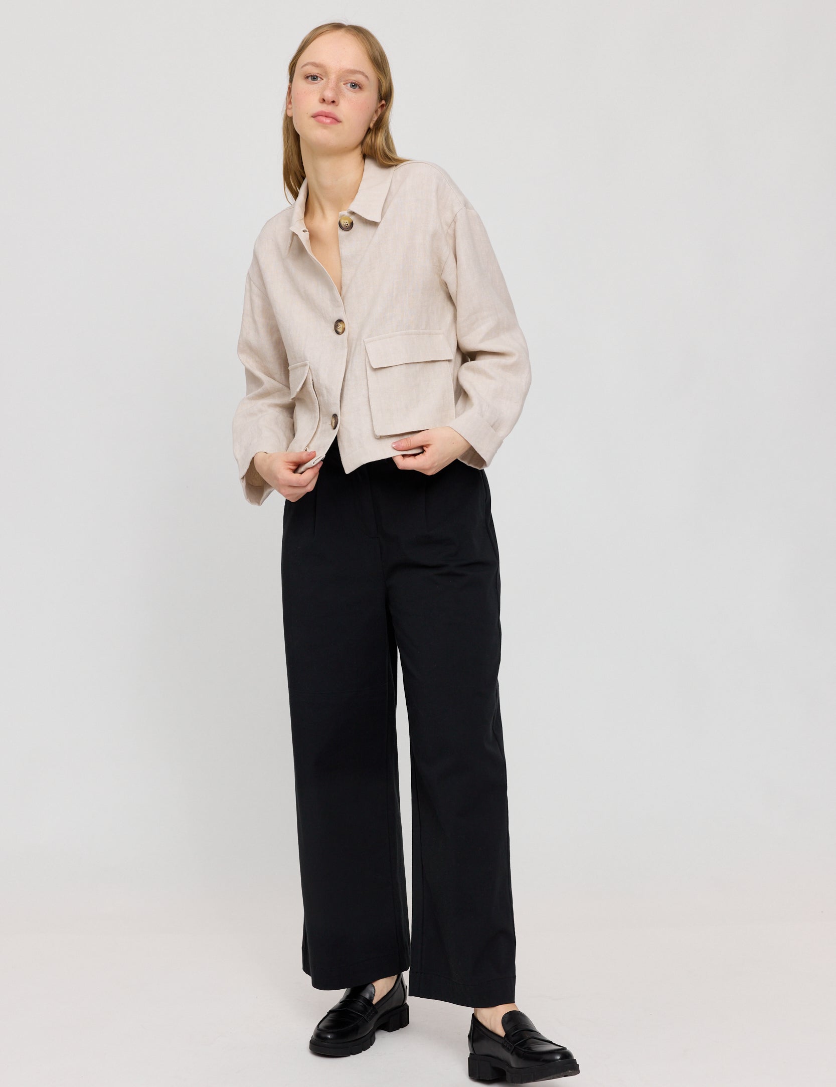 Frau in beiger Jacke und schwarzer Hose