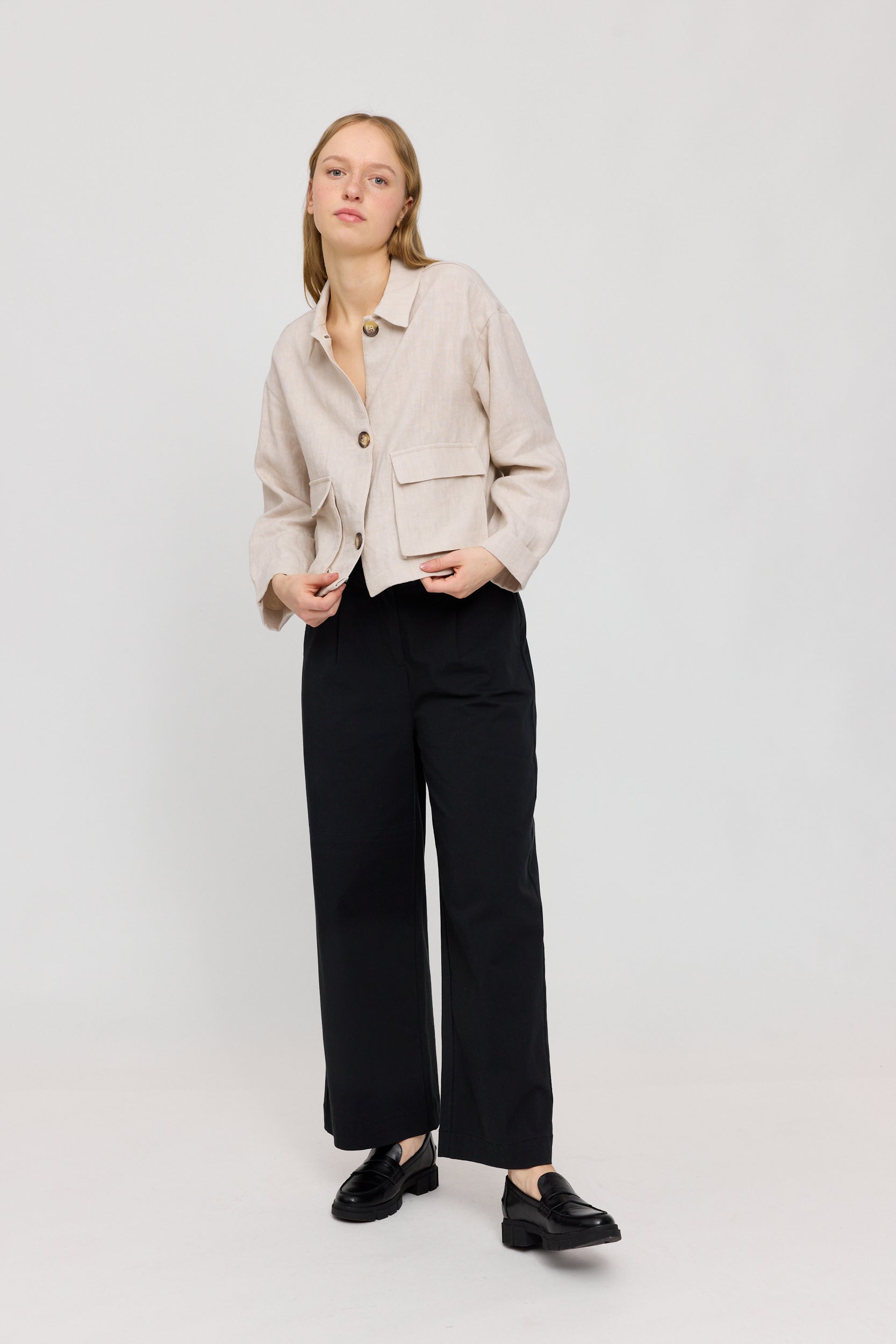Frau in beiger Jacke und schwarzer Hose