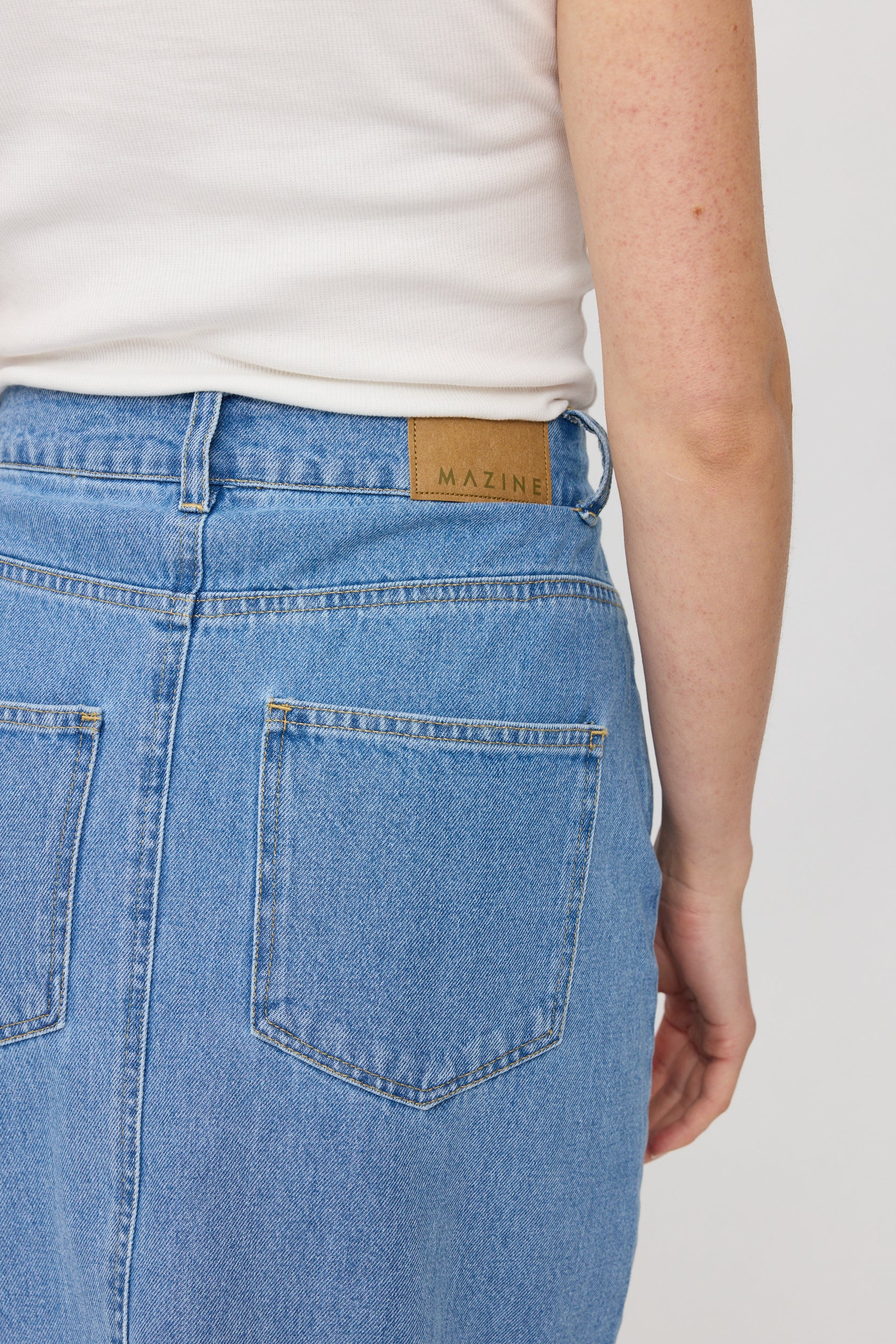 Person trägt Jeans mit Markenlabel 'MAZINE'