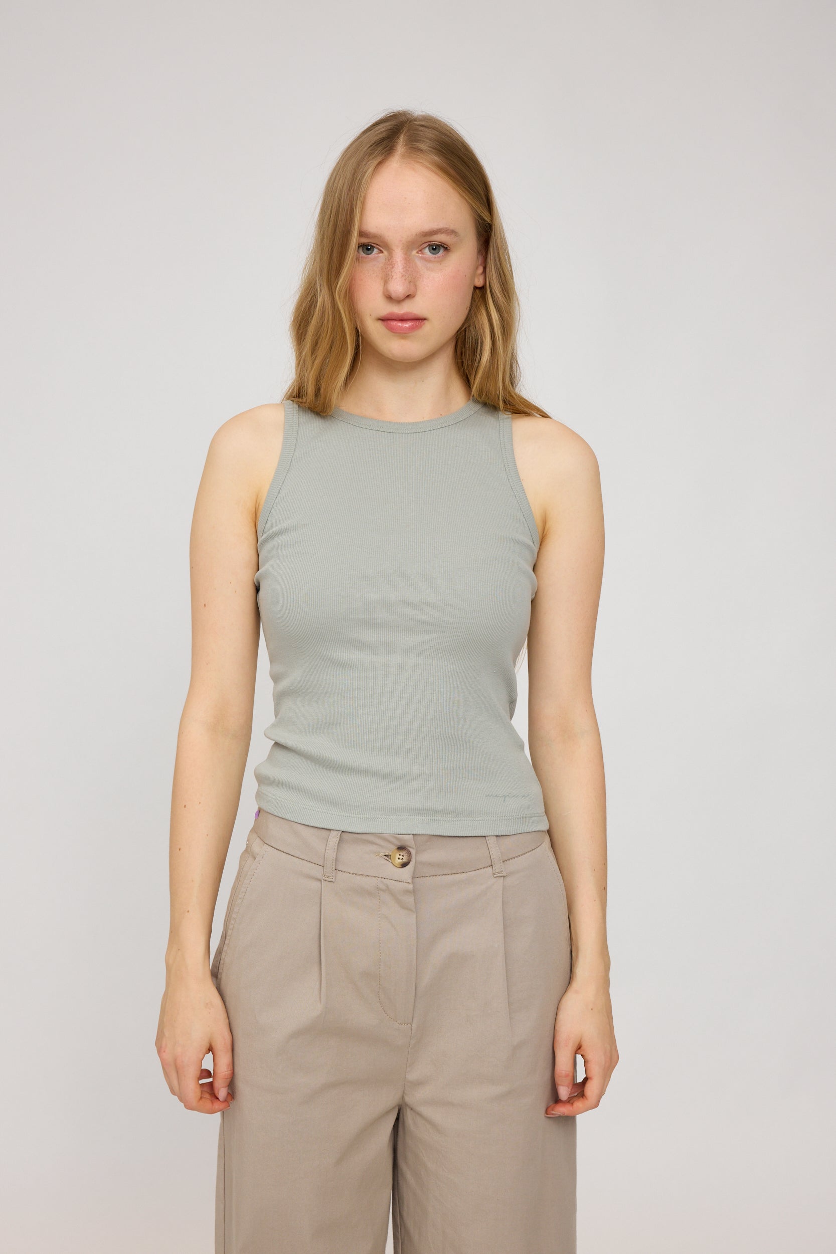 Junge Frau in grauem Top und hellbrauner Hose