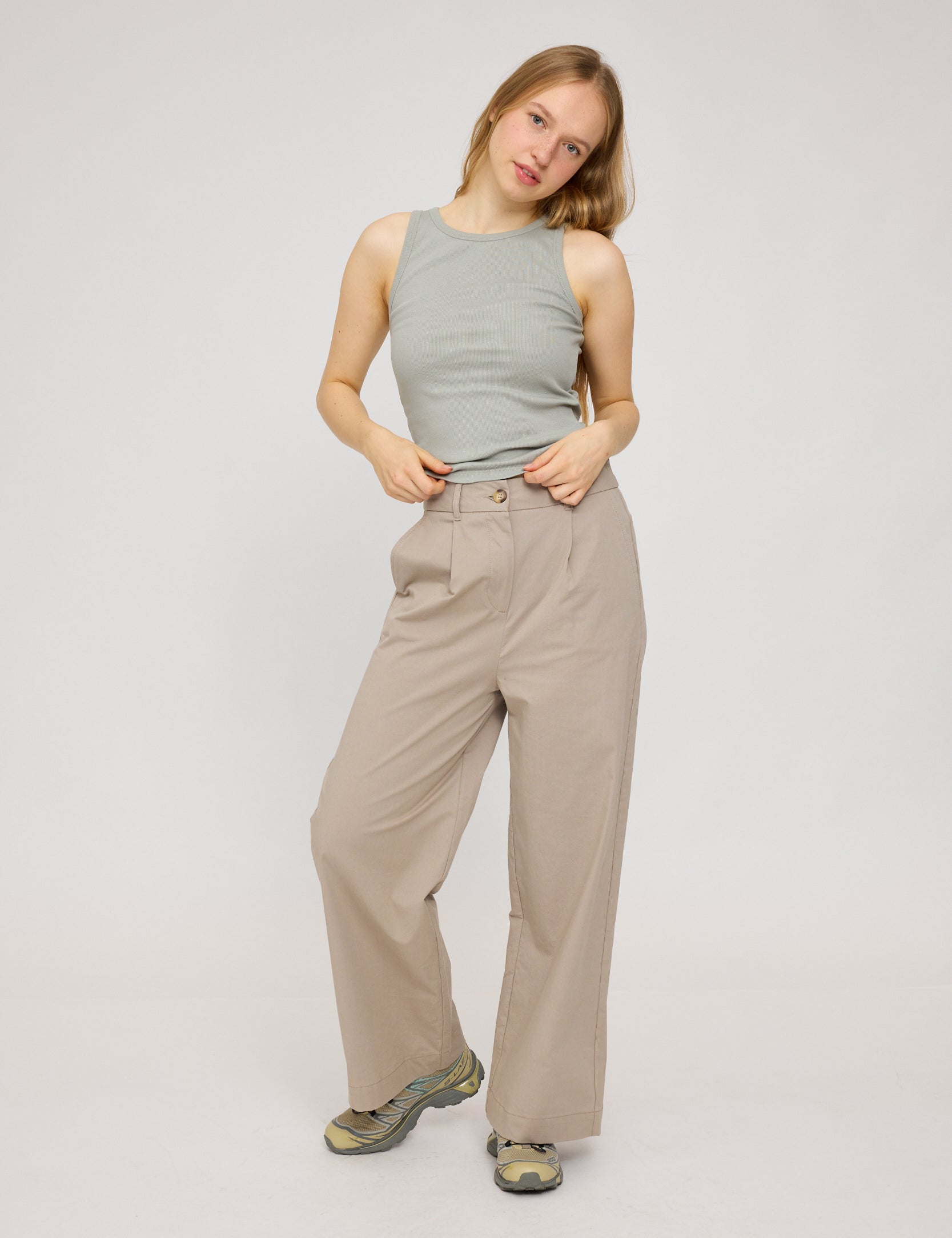 Frau in beiger Hose und grauem Top posiert