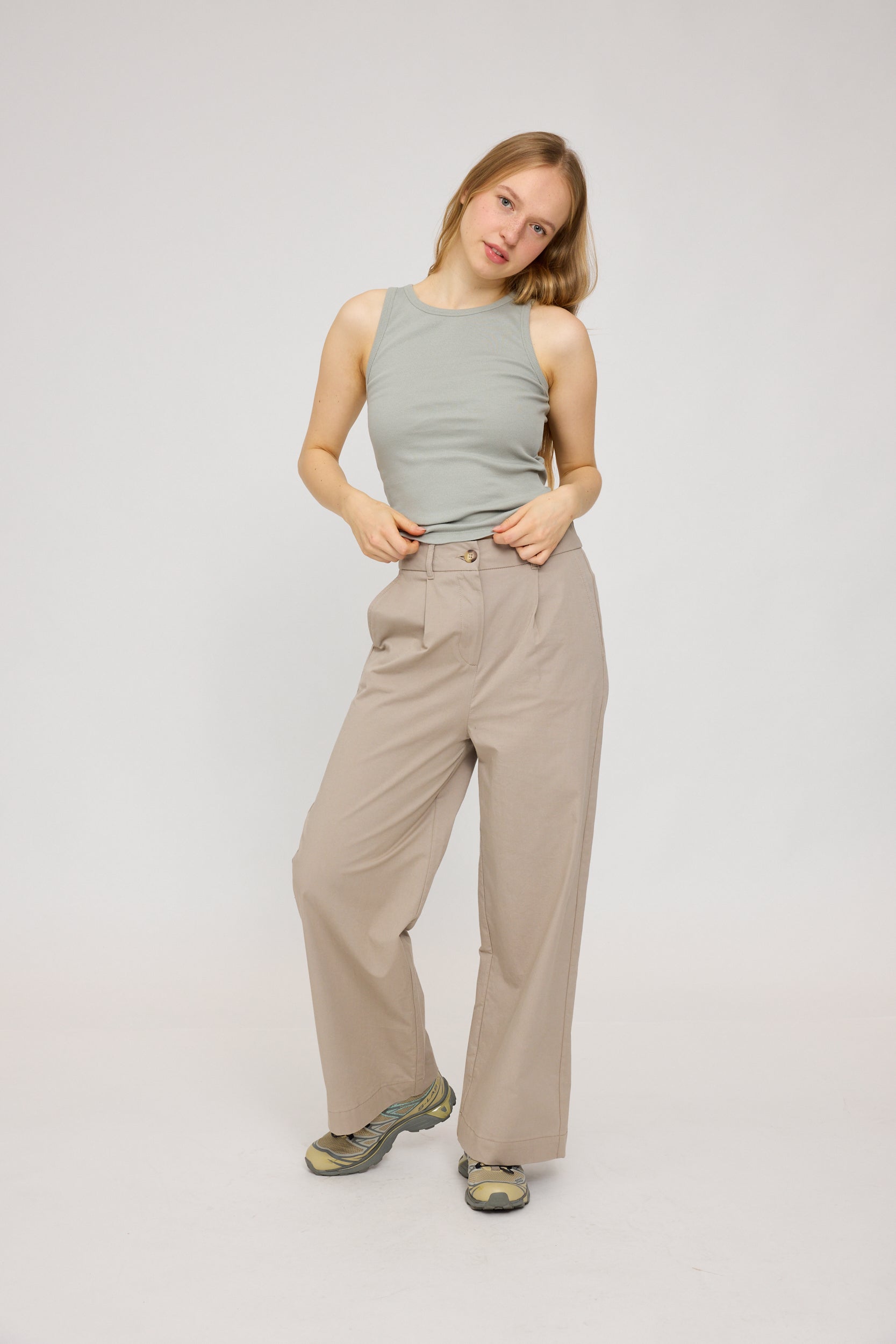 Frau in beiger Hose und grauem Top posiert