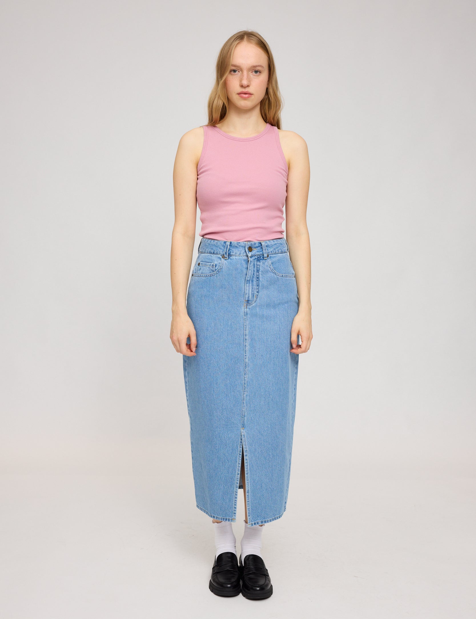 Frau in rosa Top und Jeansrock steht