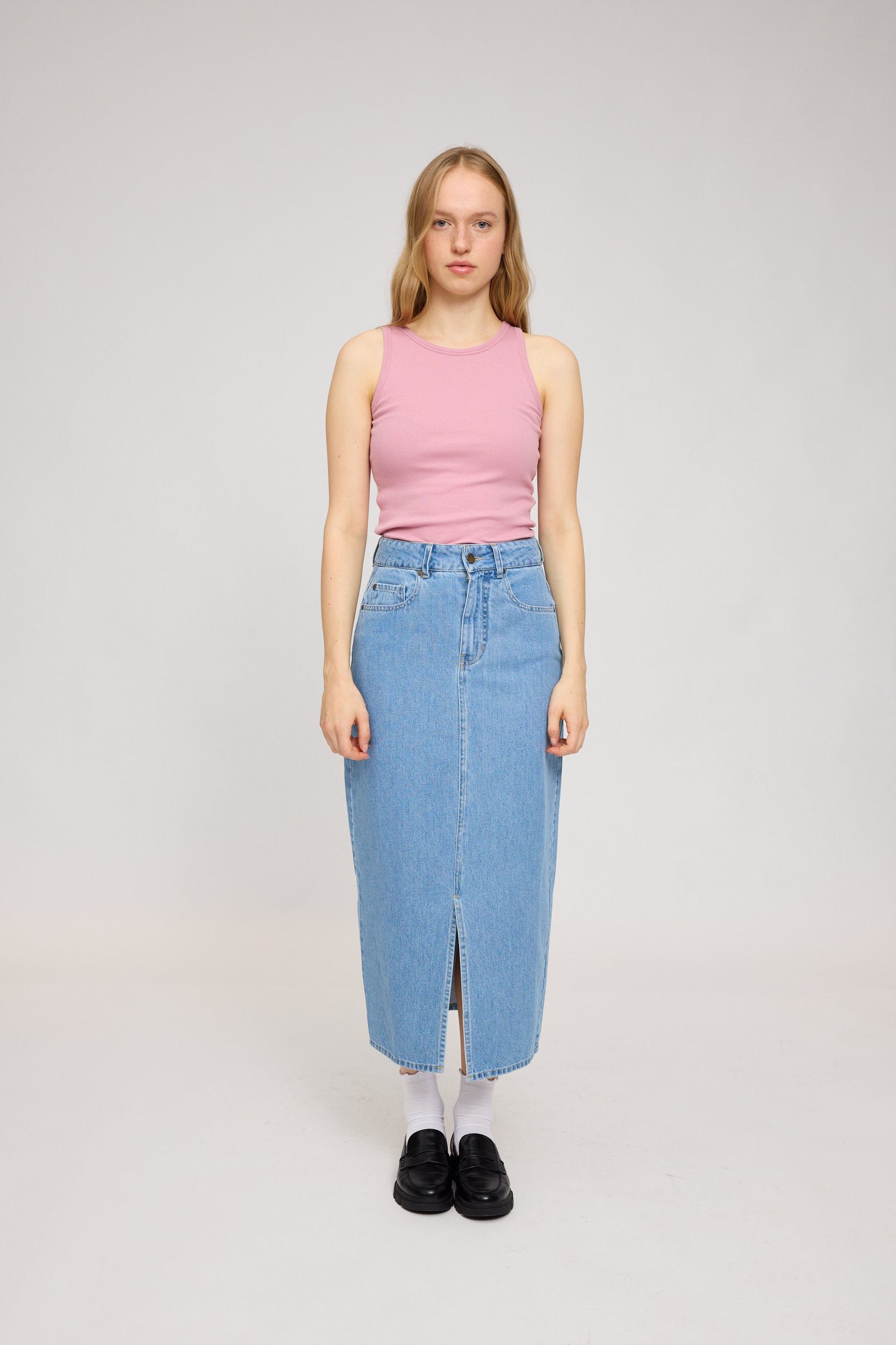 Frau in rosa Top und Jeansrock steht