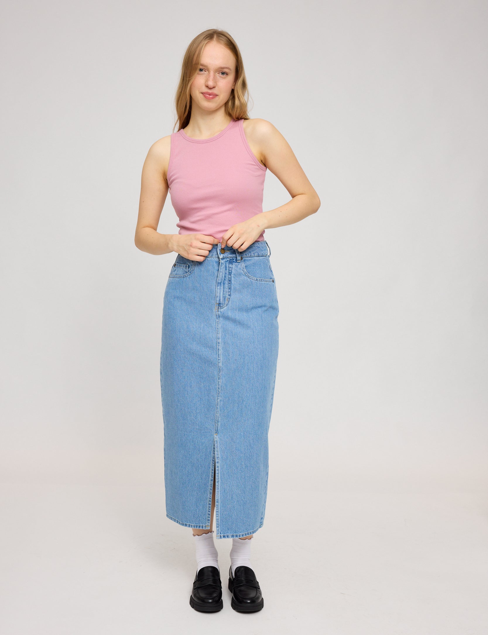 Frau in rosa Top und Jeansrock steht