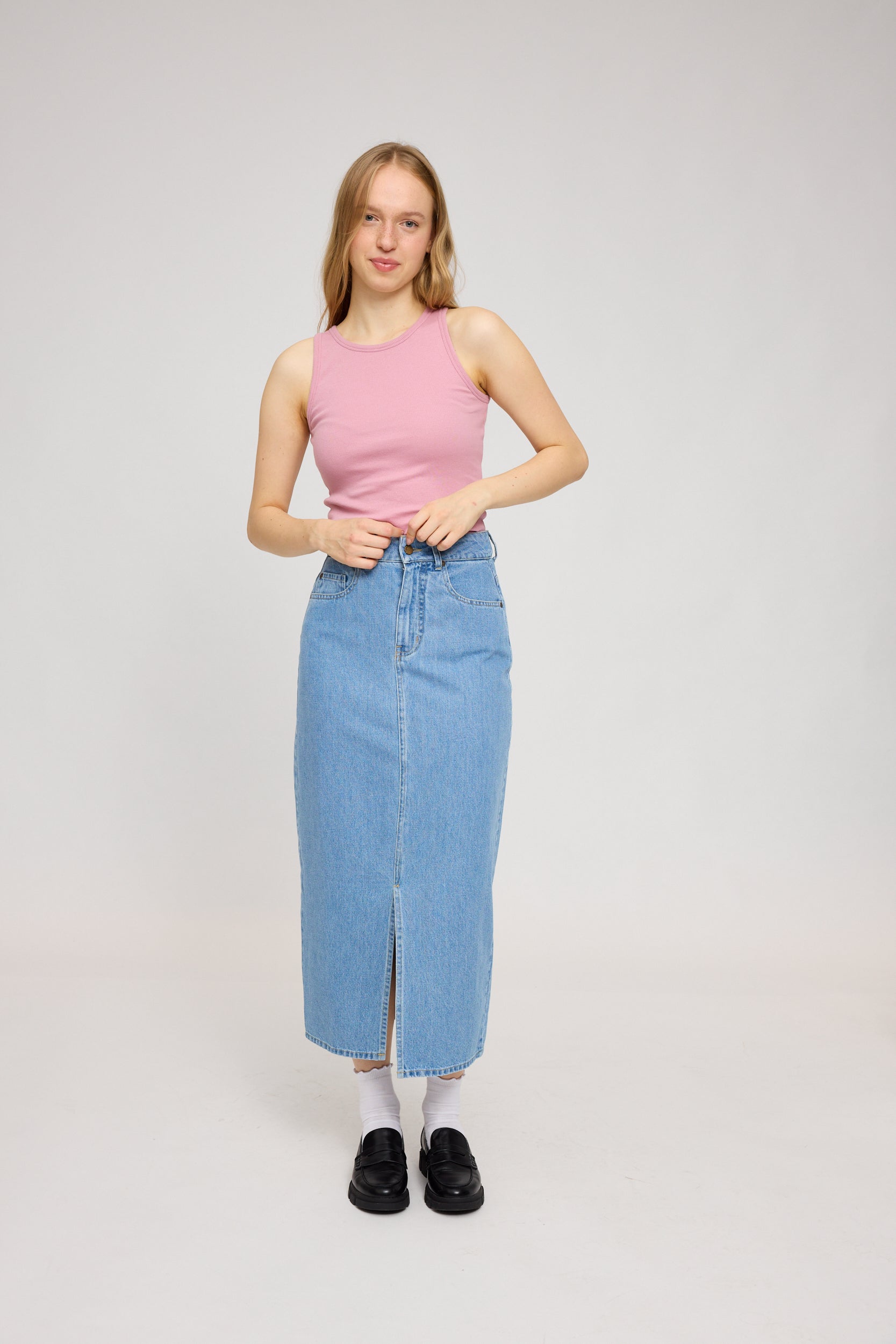 Frau in rosa Top und Jeansrock steht