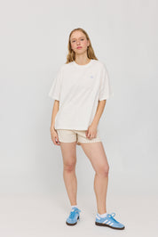 Frau in weißem Shirt und beigen Shorts