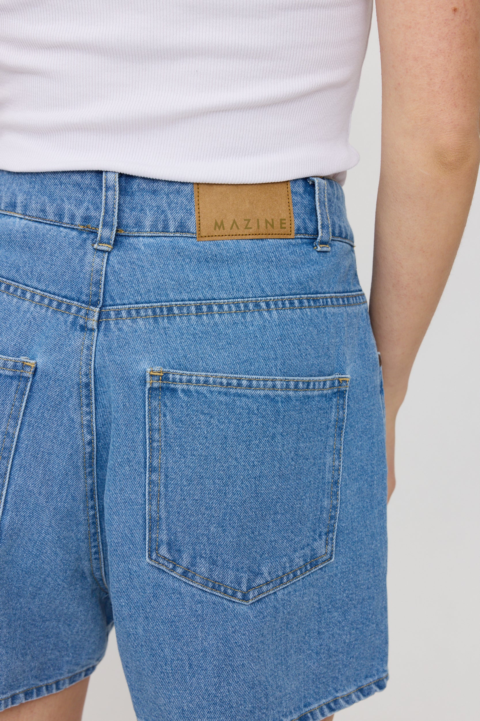 Person trägt Jeans mit Markenetikett 'MAZINE'
