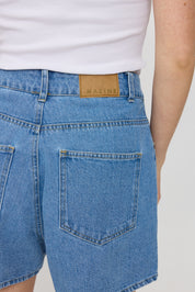 Person trägt Jeans mit Markenetikett 'MAZINE'