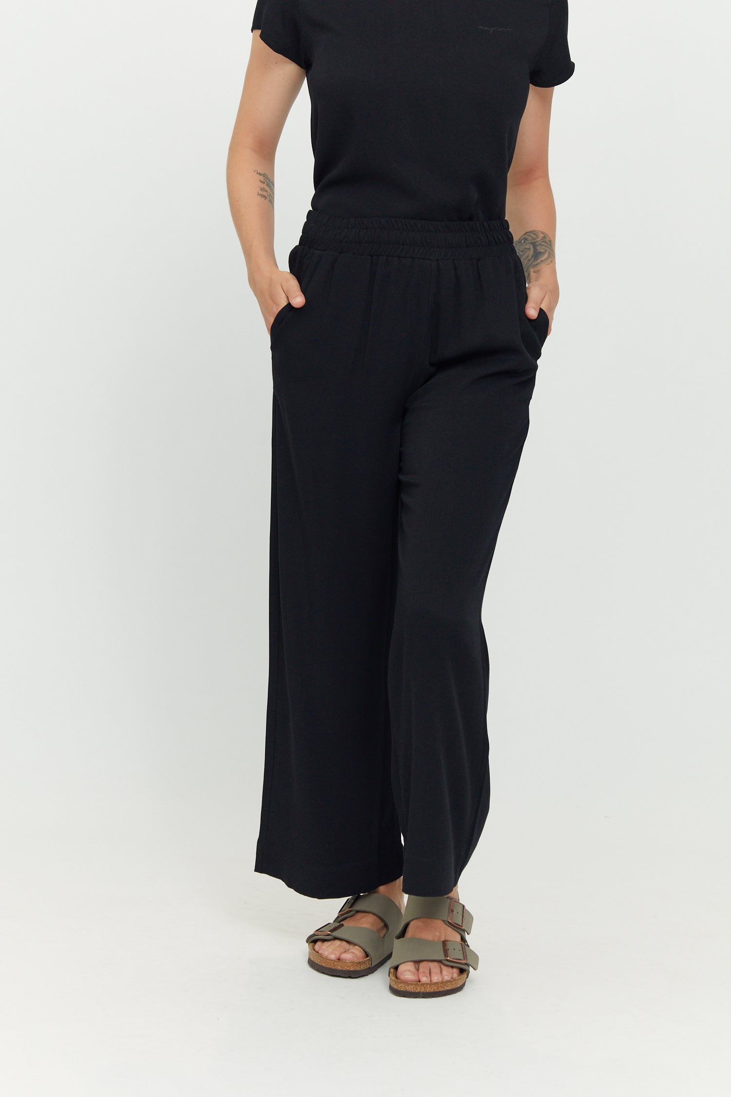 Frau in schwarzer Hose und T-Shirt posiert