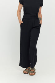 Frau in schwarzer Hose und T-Shirt posiert