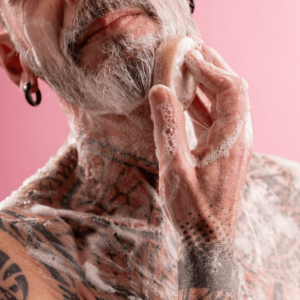 Mann mit Tattoos wäscht sein Gesicht