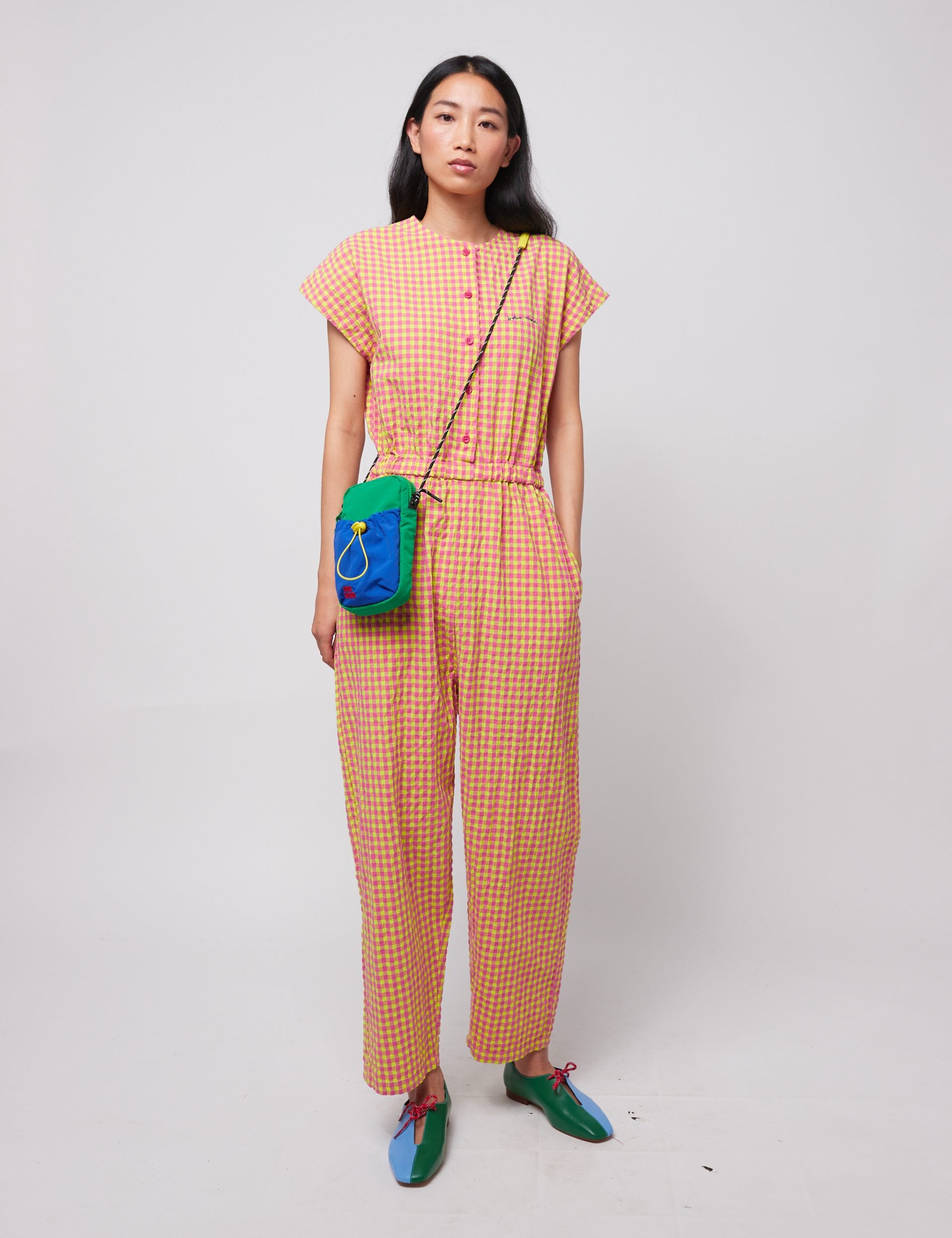 Frau mit kariertem Outfit und bunter Tasche