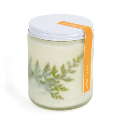Kerze in Glas mit Pflanzenmotiv und orangem Etikett