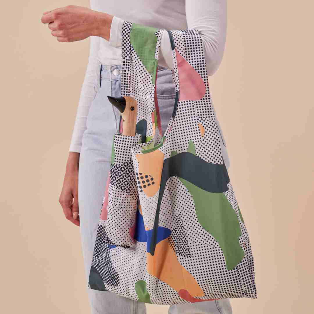 Frau hält bunte Tasche mit Holzfigur