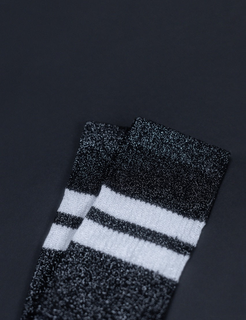 Schwarz-weiße gestreifte Glitzersocken auf dunklem Hintergrund