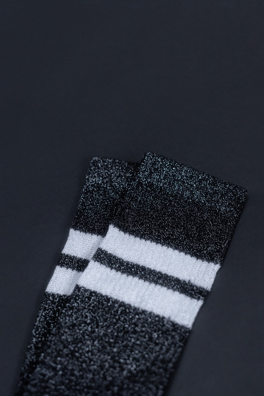 Schwarz-weiße gestreifte Glitzersocken auf dunklem Hintergrund