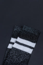 Schwarz-weiße gestreifte Glitzersocken auf dunklem Hintergrund
