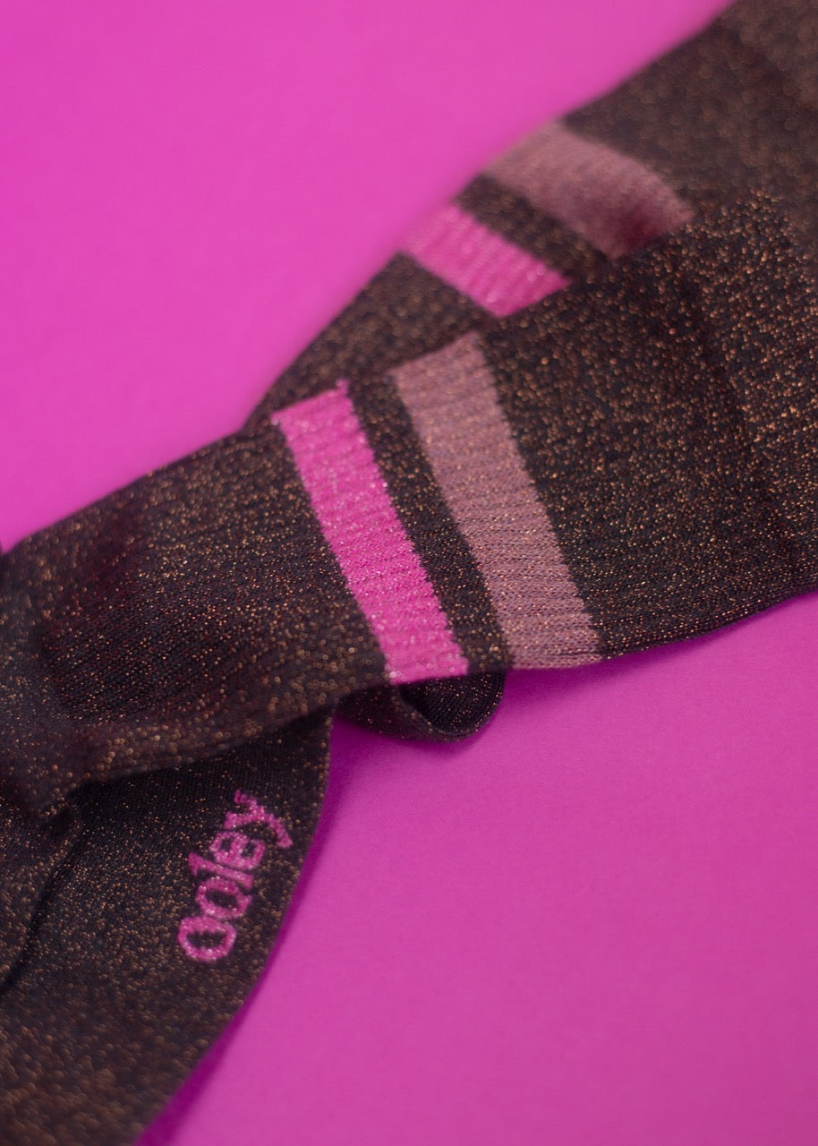 Schwarze glitzernde Fliege auf rosa Hintergrund