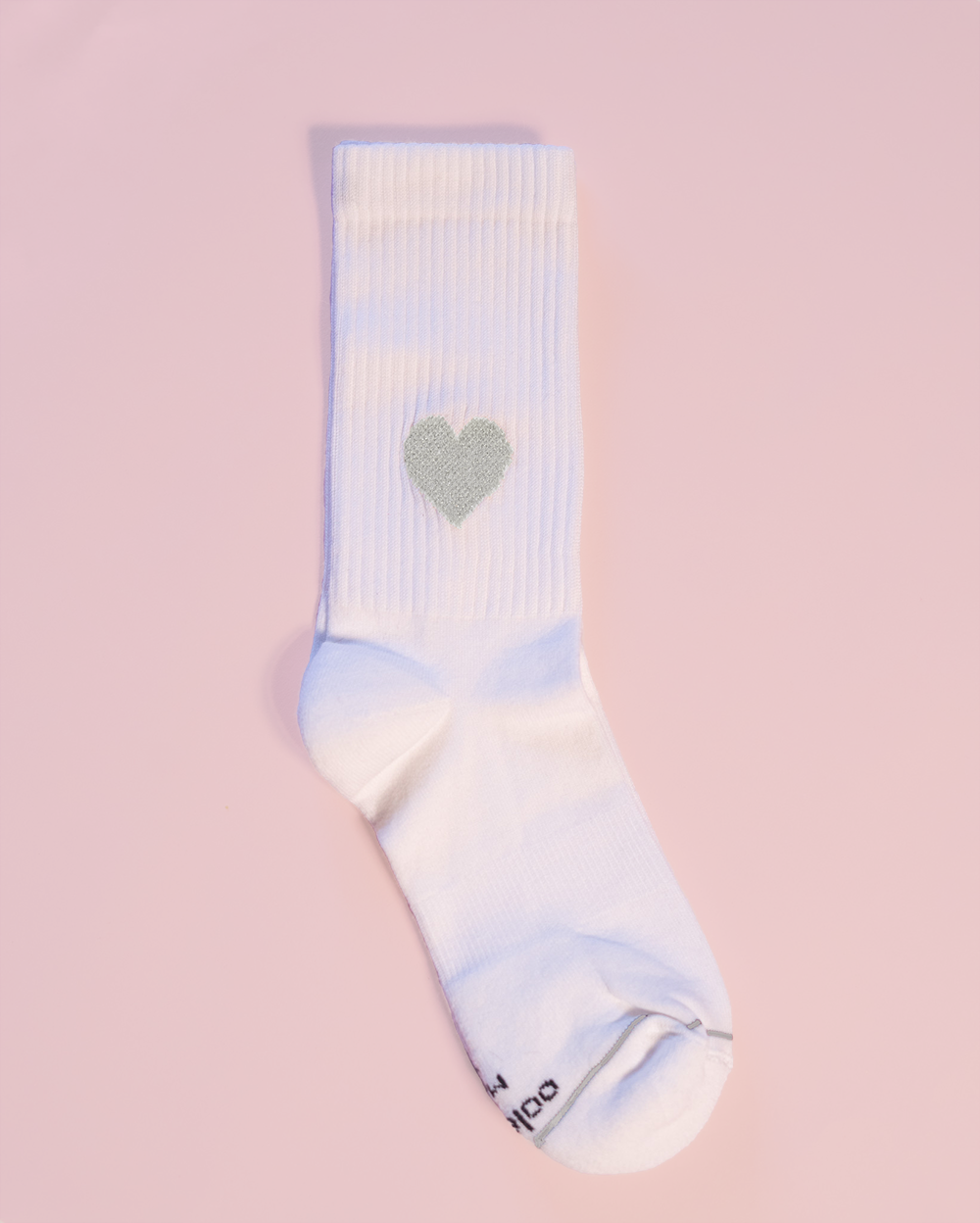 Weiße Socke mit Herzmotiv auf rosa Hintergrund