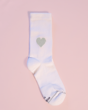 Weiße Socke mit Herzmotiv auf rosa Hintergrund